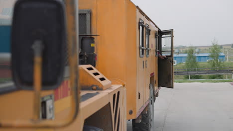 Workers-in-uniform-get-in-big-orange-vehicle-closing-doors