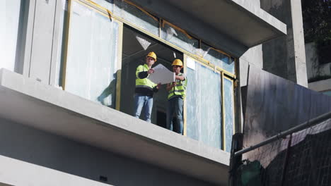 trabajadores de la construcción revisando planes en un balcón