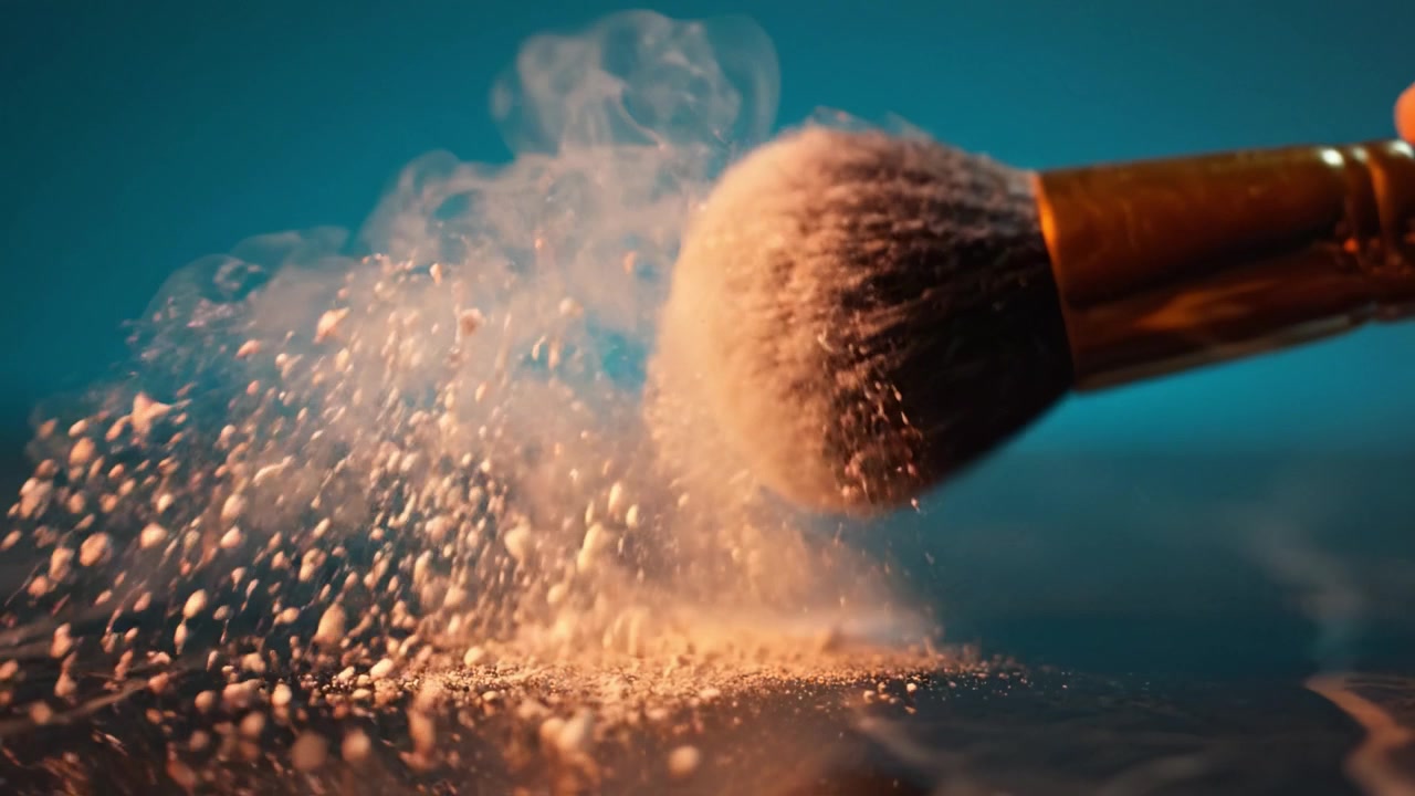 Fængslende nærbillede af en makeupbørste, der drysser pudder på en reflekterende overflade, omgivet af en tåget baggrund, og viser skønhed og elegance i aktion.