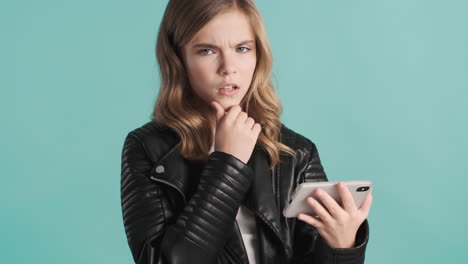 Teenage-Caucasian-girl-in-leather-jacket-watching-videos-on-her-smartphone.