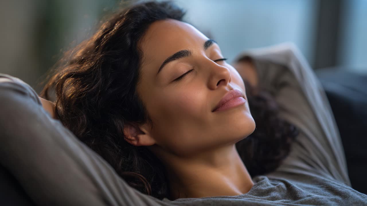 Momenti sereni di relax: una donna che si rilassa in serena contemplazione con gli occhi chiusi e un sorriso dolce sul viso in un ambiente accogliente