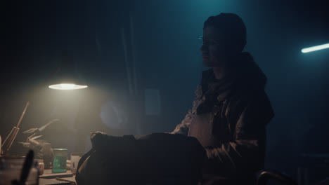 a bombmaker assembles a bomb in his workshop at night