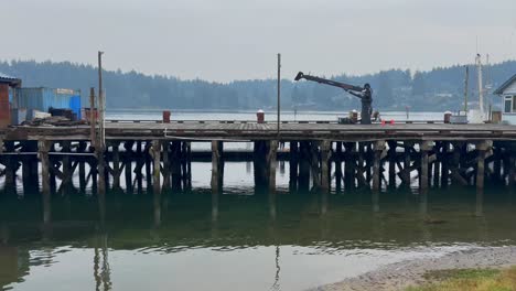 viejo muelle de pesca de madera sobre el agua con árboles en el fondo en un día nublado