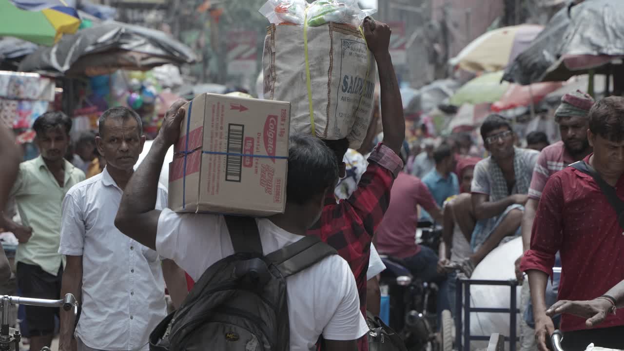 Bustling Street Scene with People Carrying Goods in a Market