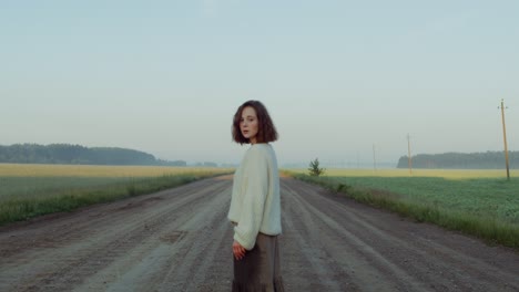 woman standing on a country road at sunrise/sunset