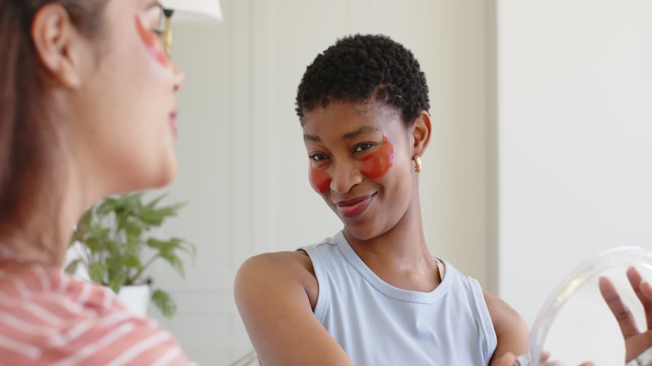 Diverse women at home friend talking as African American woman holding mirror red patches smiling