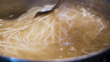 stirring a pot of boiling noodles in slow motion