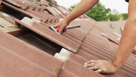 roofer fixes roof with tiles, medium shot of man at work