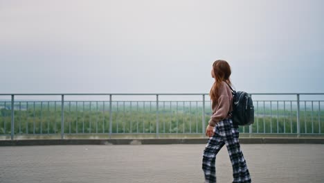 teenage girl walking on a bridge