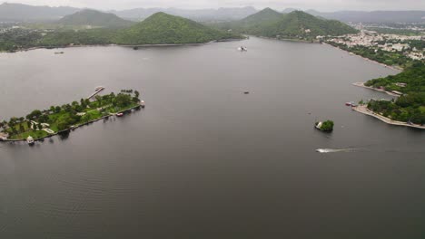 dolly aéreo revelando lancha rápida navegando por un gran lago en udaipur, india