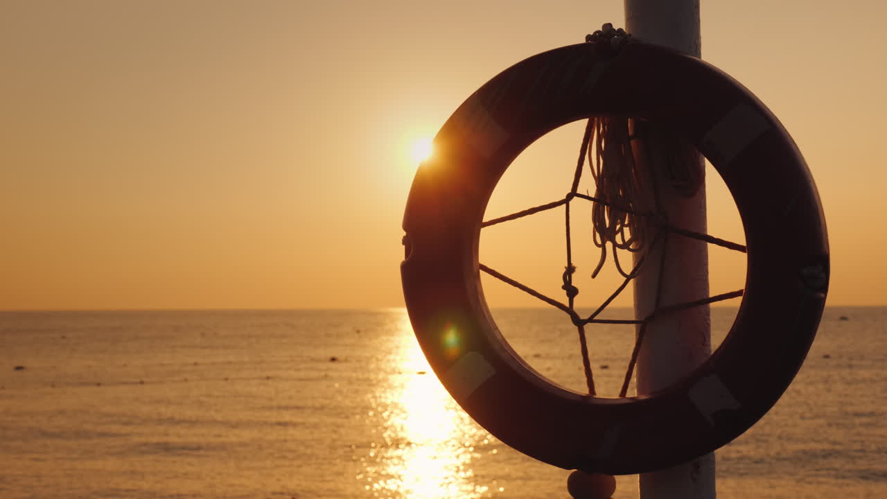 un salvavidas cuelga contra el fondo del mar donde sale el sol video 4k