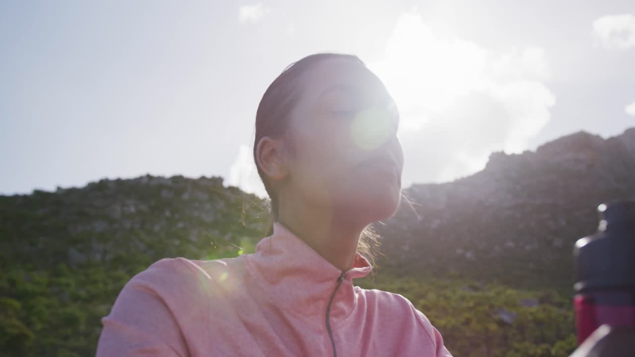 웃는 시골에서 운동하는 동안 물을 마시는 혼성 인종 여성