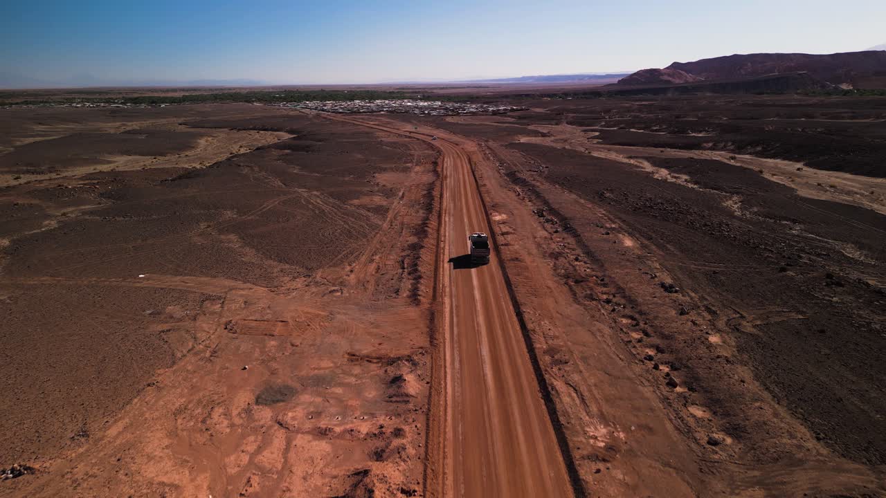 camión conduciendo en un camino polvoriento a través del paisaje desértico chileno, fotografía aérea a la luz del día