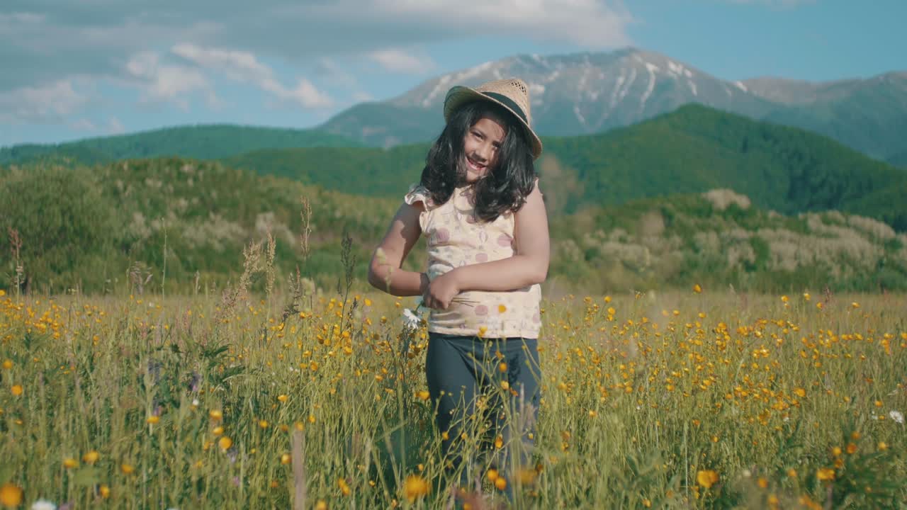 niña con sombrero en el prado de la montaña