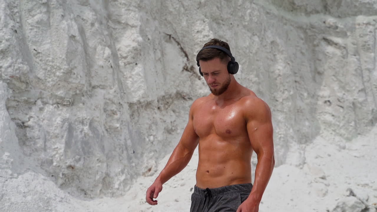 Active sport fitness. Portrait of muscular man listening music during training on nature