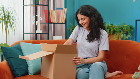 Feliz-Mujer-árabe-Compradora-Desempacando-Caja-De-Cartón-Paquete-De-Entrega-Compras-En-Línea-Compra-En-Casa