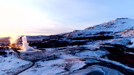 panoramic view with a drone of mountains under the red sunset in geysir, iceland. there is geysers in the wonderful famous place for travelers. a lot of smoke is getting out of the geyser.