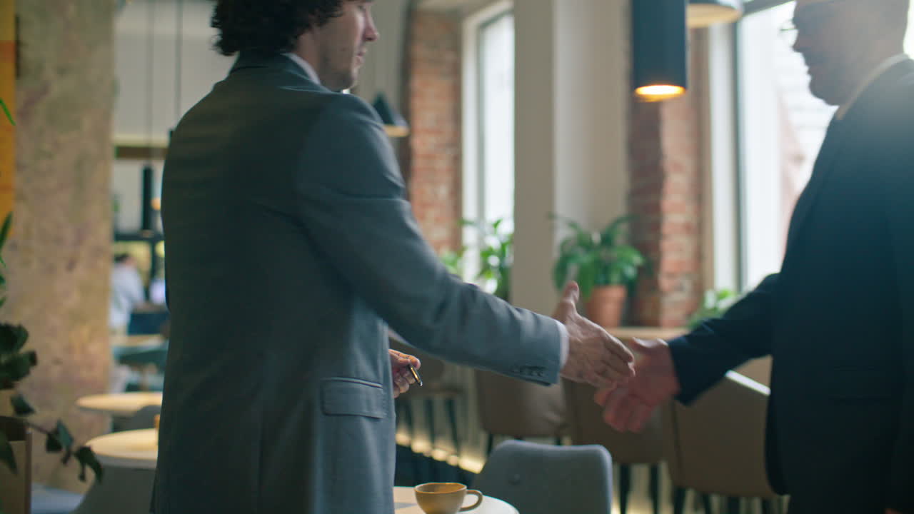 Two Businessmen Meeting in Cafe, Shaking Hands and Having Discussion
