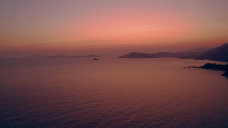 Hermosa-Toma-De-Drones-De-Una-Costa-Natural-Durante-La-Puesta-De-Sol,-La-Luz-Es-Clara,-Roja-Y-Dorada-Y-El-Mar-Refleja-Esos-Colores