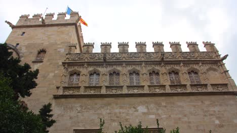 Antiguo-E-Histórico-Edificio-De-La-Lonja-De-La-Seda-Con-Banderas-En-Valencia,-España