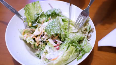 cutting some salad greens into smaller bite-size cuts using a knife and a fork, in a restaurant in bangkok, thailand