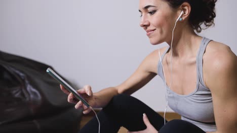 smiling sportswoman using smartphone at home