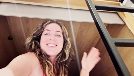 young woman looking up playfully from bunk bed with ladder, hostel