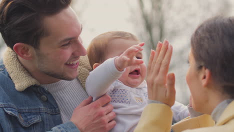 Transgender-Parents-Playing-Peek-A-Boo-With-Baby-Son-On-Walk-In-Autumn-Or-Winter-Countryside