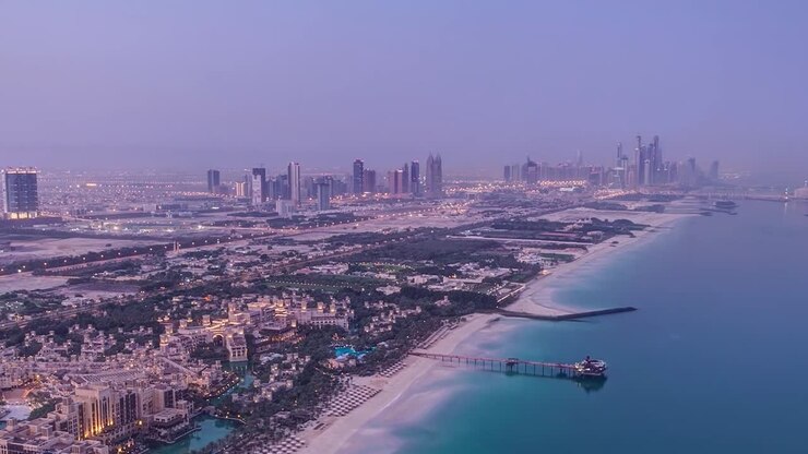 Séquence aérienne en accéléré de Dubaï, Émirats Arabes Unis, présentant un mélange de développement urbain moderne et de littoral naturel. Bâtiments résidentiels et de style complexe hôtelier avec piscines et verdure.