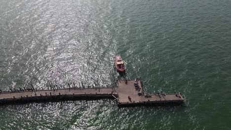 reverse aerial footage of the tip of pattaya fishing dock showing a fishing boat and the end of the pier, pattaya, thailand