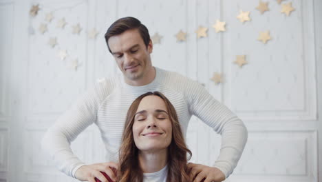 pareja sonriente relajándose con masaje en una habitación decorada navideña.