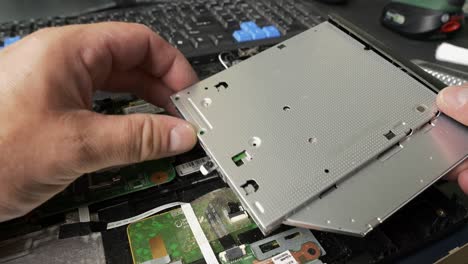 Repair-of-an-old-laptop,-the-technician-is-removing-the-CD-drive