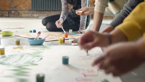 close up of unrecognizable environmental activists painting placards sitting on the floor