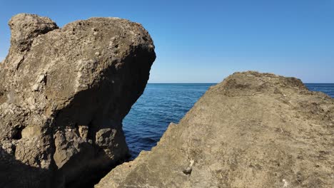 Visitors-admire-the-rocky-coastline-of-Crimea,-enjoying-the-clear-blue-waters-and-bright-sky-while-taking-in-the-scenic-beauty-of-the-landscape