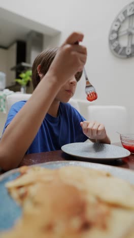 boy eating pancakes with strawberries
