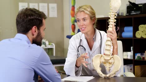 physiotherapist explaining spine model to patient