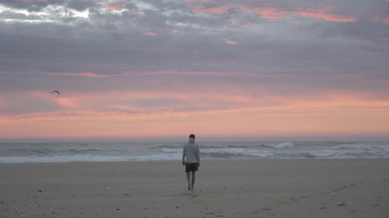 hombre caminando por la costa al atardecer en la playa en sudáfrica