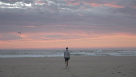 Man-walking-along-coast-at-sunset-on-beach-in-South-Africa