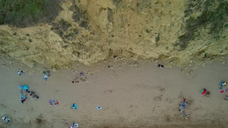 rising aerial shot moving up bridport west bay sandstone cliffs above sandy beach coastline