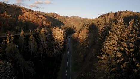 Dramatic-aerial-establishing-shot:-Cars-speed-on-straight-road-by-scenic-dam