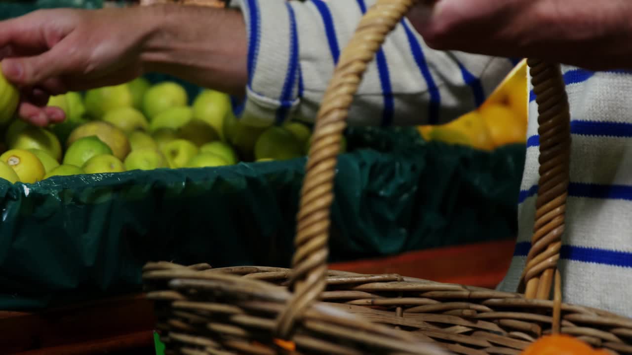 Male shopper reaching bin selecting apples placing in wicker basket for shopping HUD tracking hands