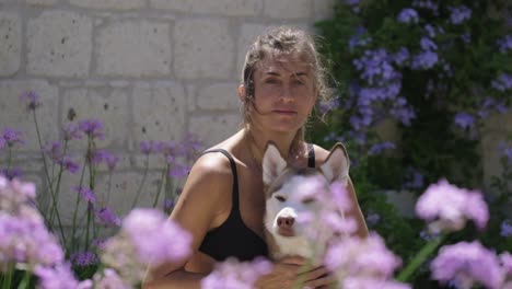 Woman-hugging-her-dog,-looking-towards-the-camera