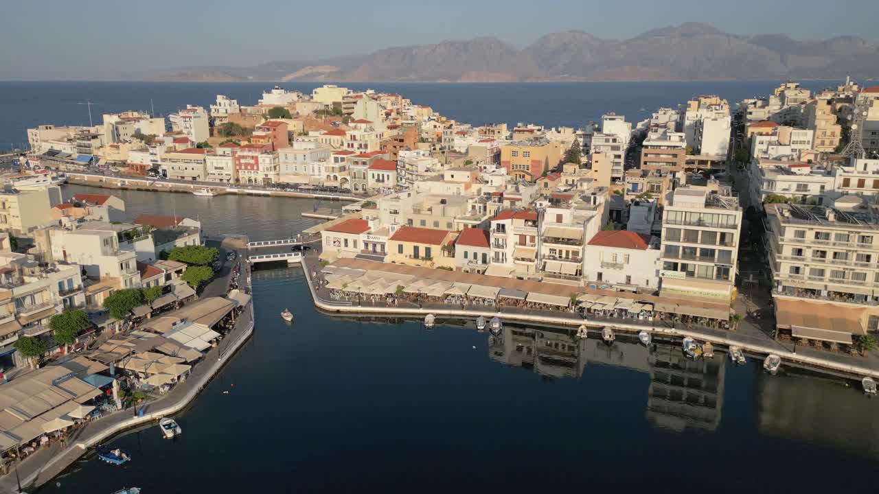 Agios Nikolaos'un geleneksel mimarisini, kıyı şeridinin cazibesini ve nefes kesen Girit manzarasını yukarıdan yakalayan kusursuz bir yatay drone çekimi