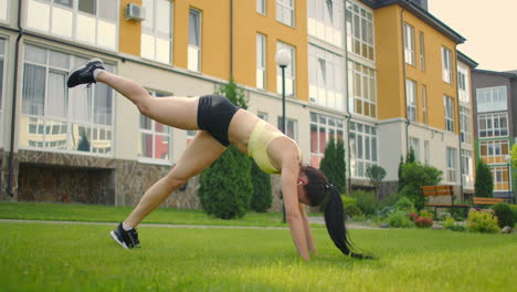 Clases-De-Yoga-Con-Auriculares-Escuchando-Música-En-El-Parque-De-La-Ciudad-En-Verano.-Pistas-Y-Calentamiento-Antes-Del-Entrenamiento.-Una-Deportista-En-El-Césped-Hace-Yoga.