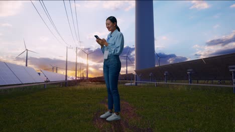 full body side view of asian female with her phone with solar panel and wind turbines, working continuously with her phone
