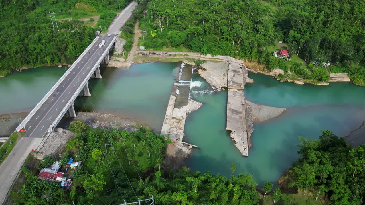Scenic aerial tilt-up reveal of dam along Sto Domingo River and bridge surrounded by lush greenery at Virac, Catanduanes.
