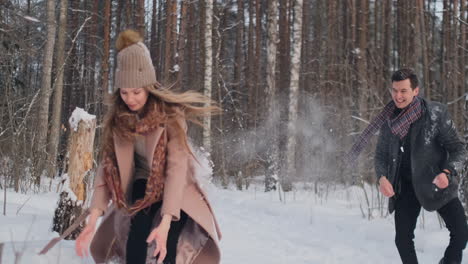 slow motion - couple snowball fighting in a field. they end their fight on a good terms with a high five.