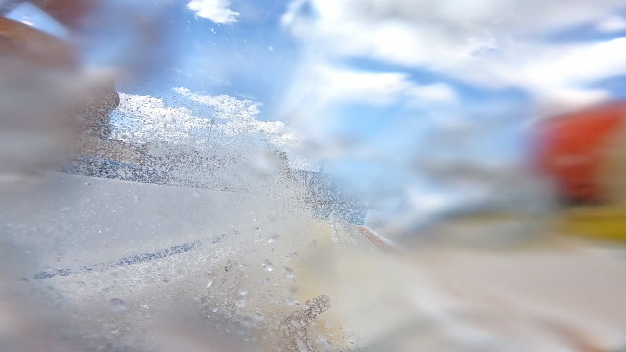 Process of getting off the water slide in summer day. Man goes down from water roller coaster into the swimming pool. Happy time inside the colorful pipe in aqua park.