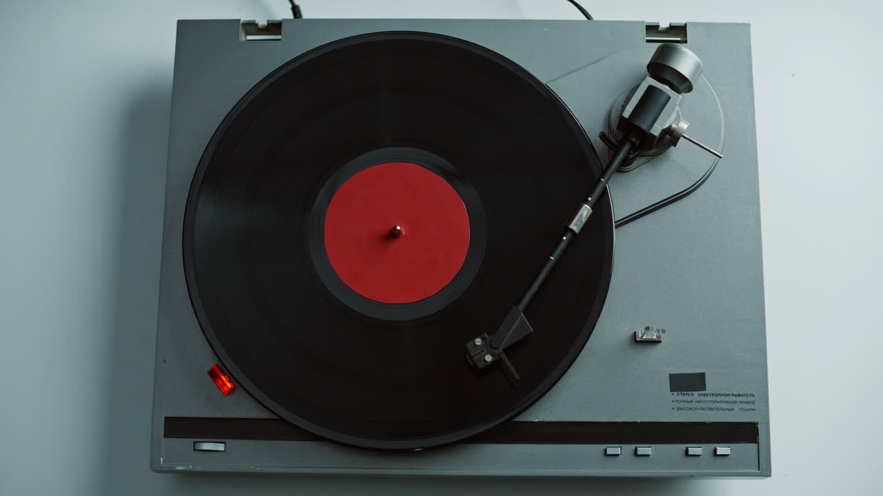 Hand taking gramophone tonearm starting music playing in apartment closeup