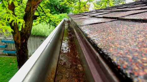 rain water is seen pouring off shingles into a rain gutter